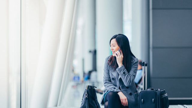 Web-Businesswoman talking on smartphone in airport