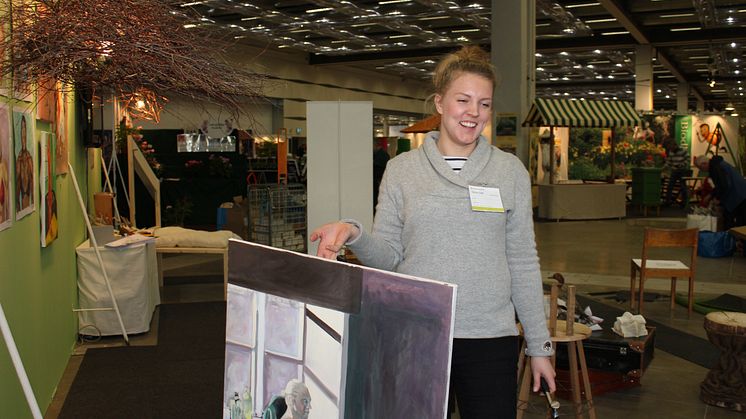 Felicia Kilander, hänger konstskolan Basis elevers konst i montern 