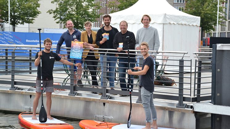 v.l. J. Hesse (Kiel-Marketing), N. Grenz (Deichperle), N. Grimm (Musikprogramm), R. Pasternak (Kulturreferent LH Kiel), F. Pape ( Alte Mu Impuls-W Kiel) v.l. auf den SUPs M. Krusenbaum (Surf Shop Kiel), F. Ehlers (Ocean Global Verlag) 