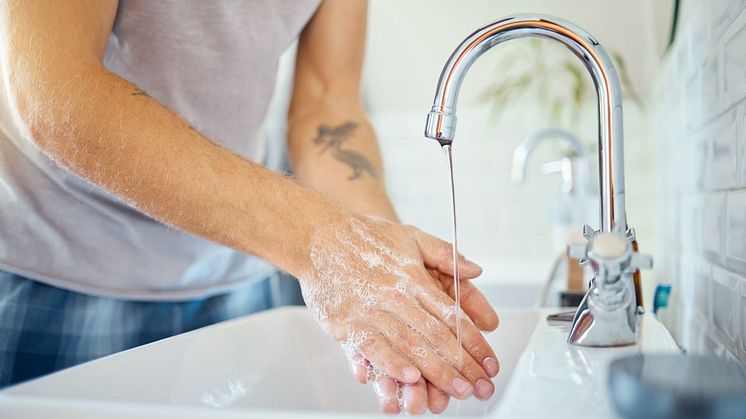 Person tvättar händerna i handfat 