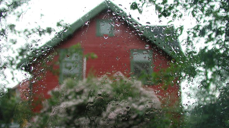 regn på vindu mot rødt hus