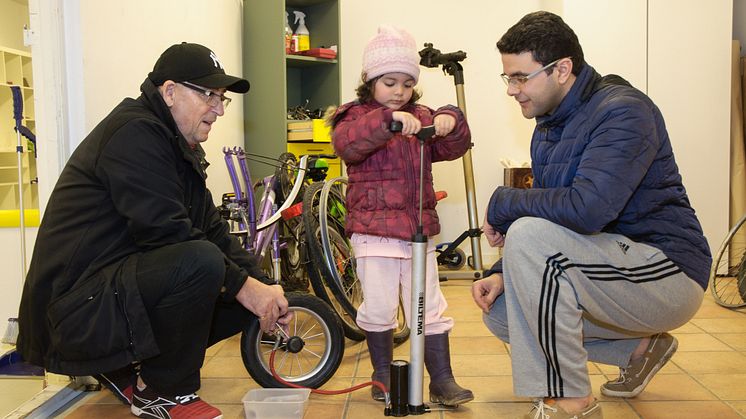 Avni Balaj hjälper Ibrahim Elgali och dottern Lina att laga däcket till en barnvagn.