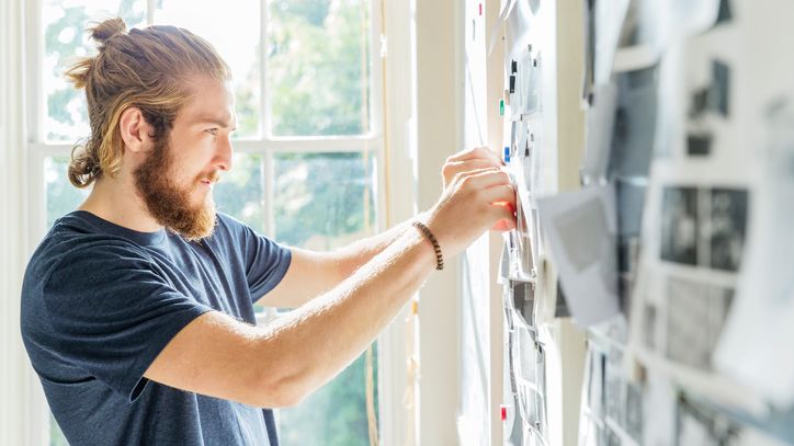 Male pinning images to noticeboard_business_Canon_GettyImages-740535201