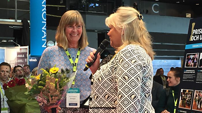 Karin Goddard, HR-Chef Riksbyggen tar emot blommor och diplom från Mona Finnström, vd Fastigo.