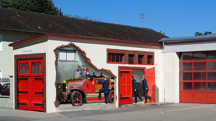 Kunst am Trafo: Historisches Löschfahrzeug am Feuerwehrhaus in Neuötting