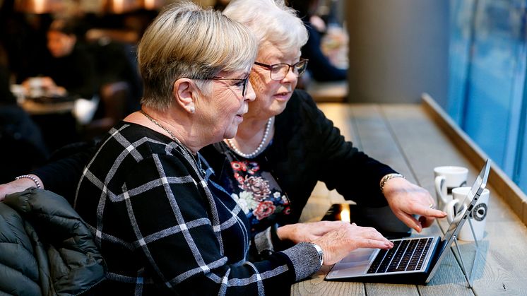 Två seniorer som surfar på ett café