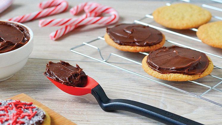 Slickepottskedens praktiska handtag lyfter upp skopan från bordsytan.