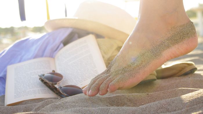Woran in den Ferien am Strand kaum einer denkt: auch die Füße vor Sonnenbrand zu schützen und vor Fußpilz, der sogar im Sand lauern kann. Bild: Wellenhofer Designs | fotolia