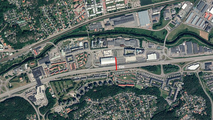 Röd linjemarkering på flygfotot visar ungefär den plats där gång- och cykelbron över E20 planeras.