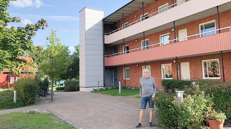 Lenny Petersson, ordförande i Brf Mönsteråshus 1, framför ett av föreningens hus som numera har en utanpåliggande hiss.