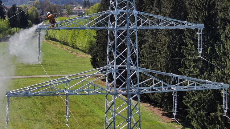 Mit dem Hochdruckreiniger werden die Masten der Hochspannungsleitung gereinigt, bevor sie einen frischen Anstrich erhalten - wie hier an einer Leitung im Landkreis Freising
