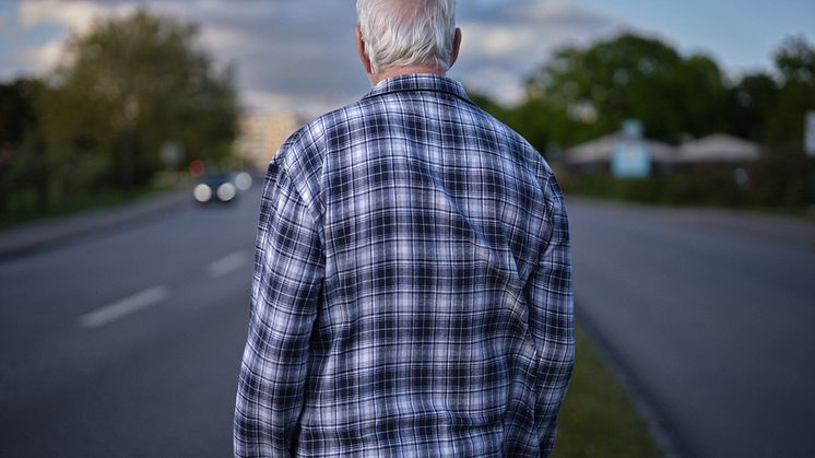 Ryggtavla av äldre man i rutig pyjamas