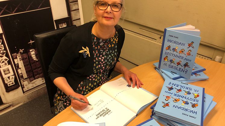 Bildebokskaper Anna Fiske signerer en bunke av sin ferske bok "Hvordan begynner man på skolen". Foto: Tanja Hoel