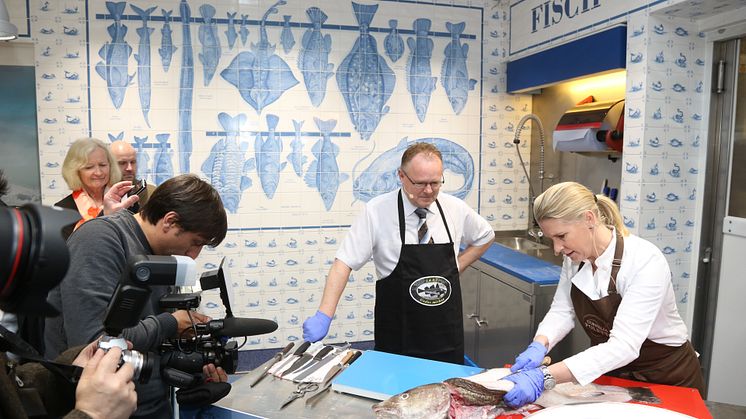 Fiskeriminister Per Sandberg og stjernekokken Cornelia Poletto viser hvordan man skal filetere en skrei.