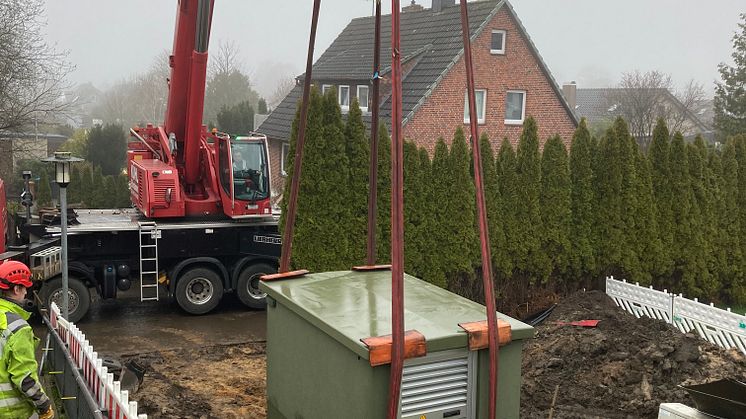 Die neue Ortsnetzstation Humsterdorf wird mit Hilfe eines Krans in Wewelsfleth aufgestellt.