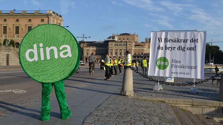 Maskot och tjänstemän från Dina Försäkringar delar ut reflexvästar till cyklister på Skeppsbron
