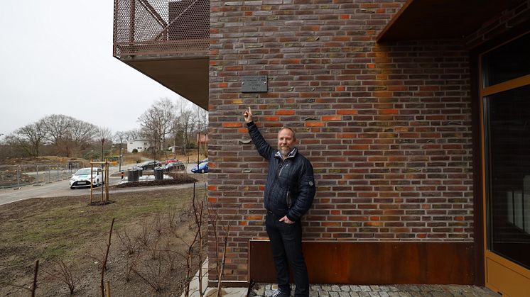Ulf Lundberg visar sin namnplakett vid Wallenstams nyproducerade fastighet Kvarteret Rosengången i Mölnlycke Fabriker.