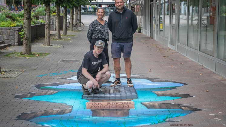 Gatukonst med konstnär. Sittande är Robert Forsberg tillsammans med Marie Andersson på Karlskoga Energi & Miljö och Johan Malmberg på Bulldozer kommunikationsbyrå.