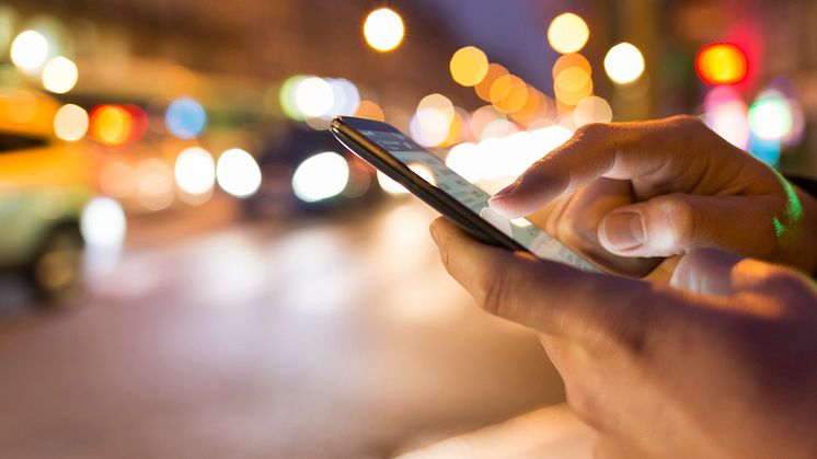 a man typing a number on his phone at night