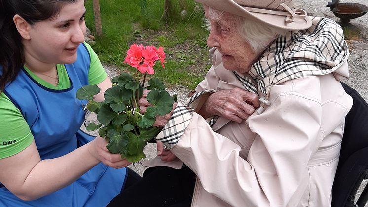 Personal och hyresgäst på Förenade Care Victoria ute i trädgården för att köpa fina blommor från butiken.