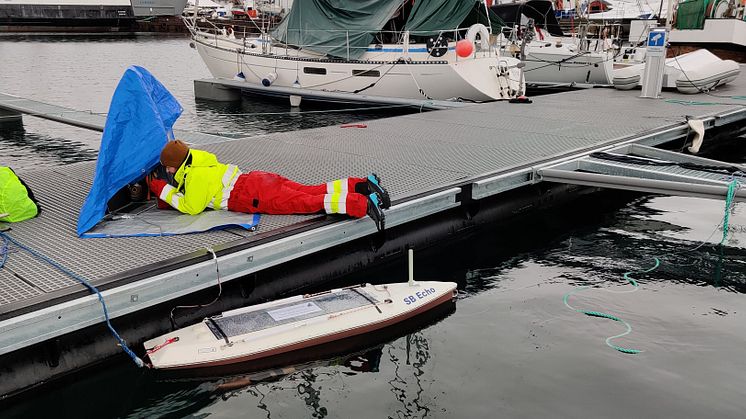 Muriel Dunn calibrating the echosounder on the sailbuoy in rainy weather (Photo: Håvard Buschmann/Akvaplan-niva).