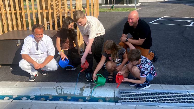 Niklas Wikström, ordförande i barn- och ungdomsnämnden och Henrik Lander, ordförande i teknik- och fastighetsnämnden fyllde tillsammans med eleverna källan på skolgården.