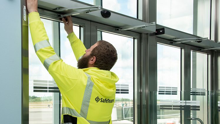 Tekniker från SafeTeam installerar dörrautomatik på dubbeldörr.