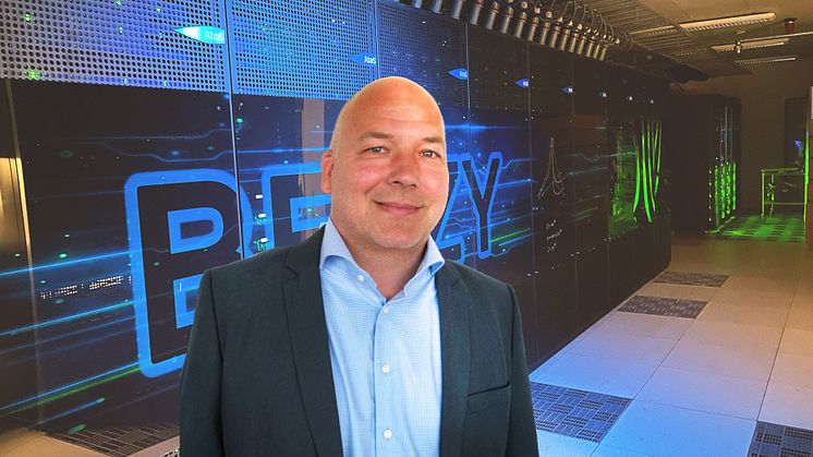 Roger Kvam i Sigma2 leder prosjektet som skal finne et egnet datasenter for Norges fremtidige HPC- og lagringsanlegg. Her foran Norges kraftigste superdatamaskin «Betzy». Foto: Sigma2.