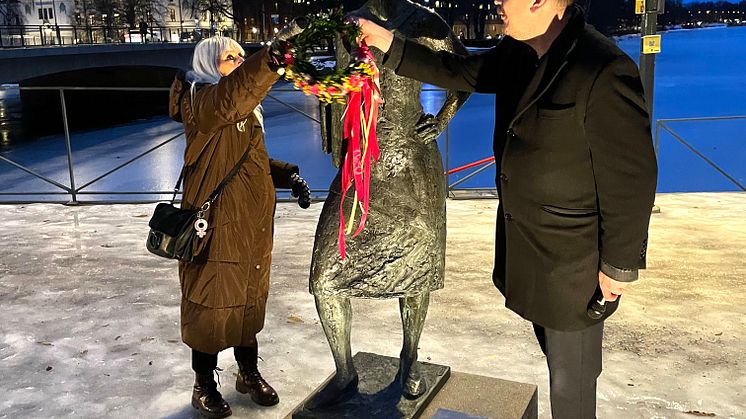 Marianne Nilsson och Robert Halvarsson smyckar skulpturen Sola i Kallsta, av konstnären Herman Reijers, med en blomsterkrans.