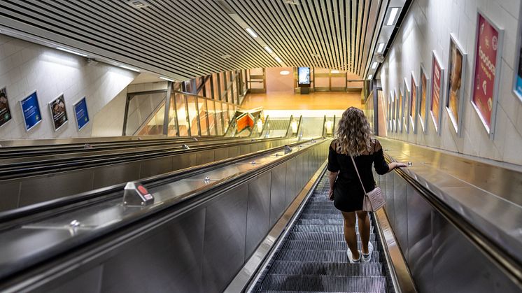 En kvinna står i en rulltrappa på en pendeltågsstation i Stockholm.
