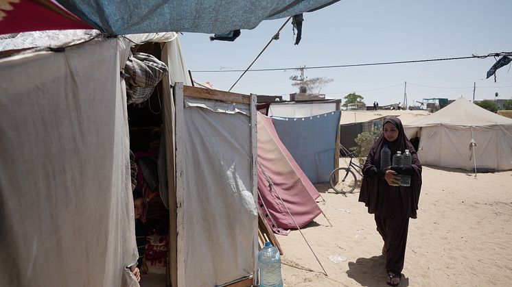 Duaa Abu Sabha håller i vattenflaskor medan hon går till sitt tält i Al-Mawasi-området i Khan Yunis. Här delar nu minst 500 000 personer på 121 toaletter. Foto: Alef Multimedia/Oxfam