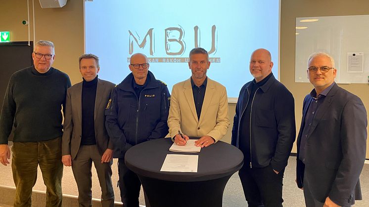 Lenny Hallgren, direktör kultur- idrotts och fritidsförvaltningen, skriver under MBU, människan bakom uniformen. På bilden syns också representanter från andra medverkande aktörer.