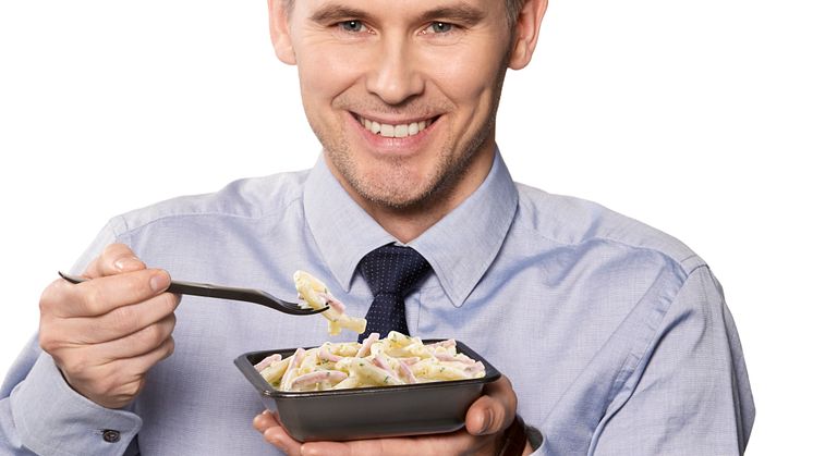En mann spiser Fjordland pasta med ost- og skinkesaus