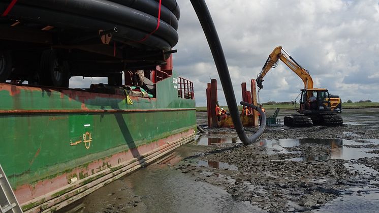 Bagger führt Schutzrohr zur Bohrung: Bei Niedrigwasser führt der Bagger das Schutzrohr zum Bohrkopf.