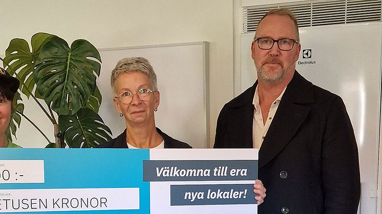 Vid invigningen tog Viola Juric, enhetschef för Slättbergsvägen 180 och Johanna Johansson, en av de boende, emot ett presentkort i stort format från Hans-Åke Erlandsson, Eidars projektledare för renoveringen och anpassningen av lokalerna.