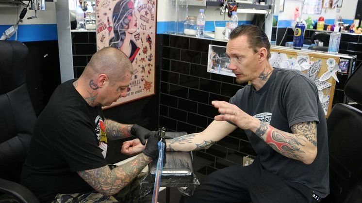 Örjan (t.h.) blir tatuerad av Rancids gitarrist Lars Frederiksen i London.