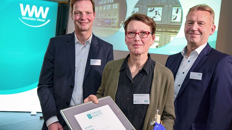 Präsentieren die Urkunde (v. l.): Jurymitglied Prof. Dr. Sebastian Braun, Preisträgerin Kristine W.-Benn und Jürgen Noch, Geschäftsführer bei Westfalen Weser.