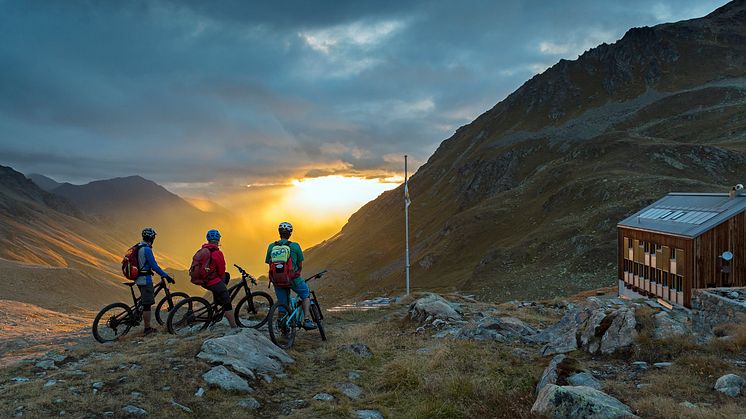 Mountainbiker genießen den Sonnenuntergang vor der Kesch Huette