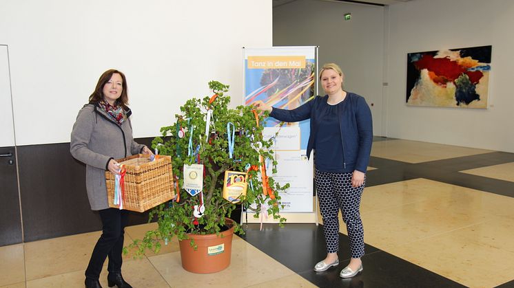Sabine Neujahr (Lions Club Corona) und Martina Seidel (Barmenia) schmücken den Maibaum in der Barmenia