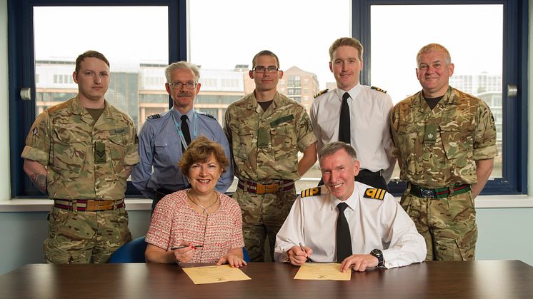 Lucy Winskell OBE from Northumbria signing the Armed Forces Covenant with Commander Ian Berry MBE RD RNR on HMS Calliope