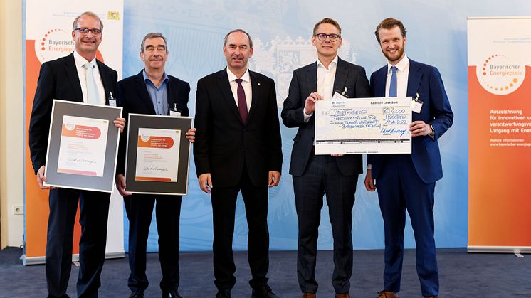 Prämiert für ein innovatives Marktmodell: Robert Pflügl und Dr. Roland Hofer vom Bayernwerk (li.) und Simon Köppl sowie Dr. Christoph Pellinger von der FfE (re.) wurden von Wirtschaftsminister Hubert Aiwanger (mi.) ausgezeichnet.