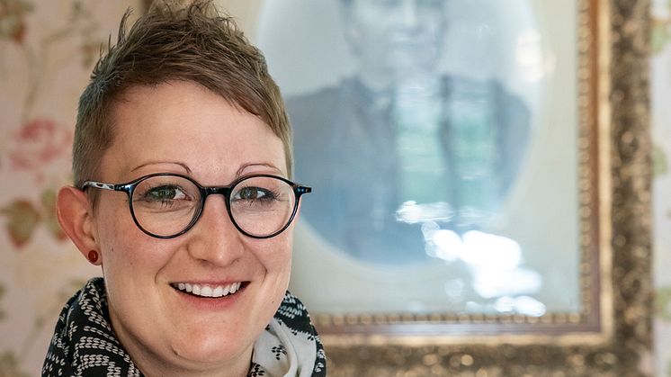 Regula Hüppi vor einem Portrait der ersten Direktorin Maria Schmid, Hotel Ofenhorn, Binn