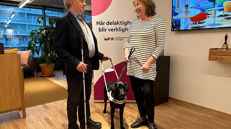 Bildtext: SRF:s förbundsordförande Niklas Mattsson räcker symboliskt över en ledarhund i sele till MFD:s generaldirektör Malin Ekman Aldén. ﻿Foto: Monica Walldén. 