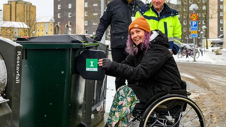 Hyresgästen Sandra provar ett nytt tillgänglighetsanpassat matavfallskärl. I bakgrunden syns Johan Paulsson, Helsingborgshem och Göran Svensson, NSR. Foto: Helsingborgshem.