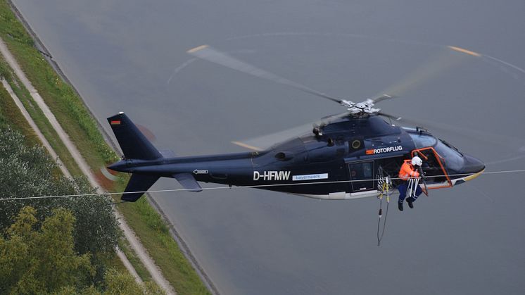 Aus dem Hubschrauber heraus montiert eine Spezialfirma am Donnerstag, 16. Juli, im Auftrag der Bayernwerk Netz GmbH Vogelschutzmarkierungen auf einer Hochspannungsleitung in Ingolstadt. Foto: Günter Drewnitzky