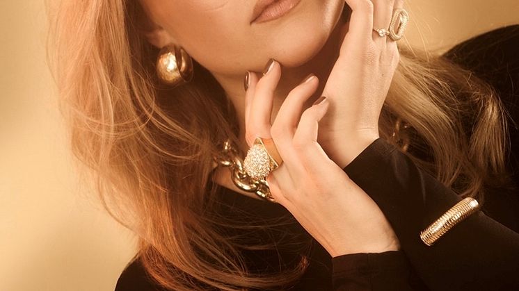 Malou Prytz blickar mot kameran. Hon bär en svart långarmad tröja, ögonskugga och större ringar och armband i guld. Foto.