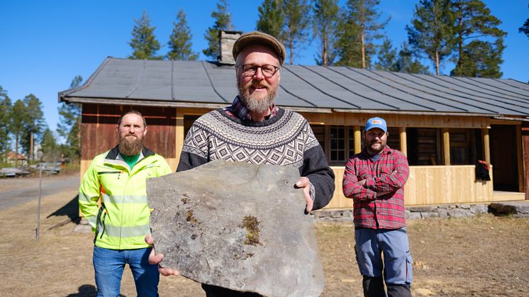 TRENGER SKIFER: Håndverker Sveinung Sletten viser med et stykke skifer som skal opp på taket på Staistua på Anno Glomdalsmuseet. Bak står driftssjef Ivar Busterud Bjørnstad (t.v.)og håndverker Henrik Josefsson. (Foto: Ali Suliman/Anno)