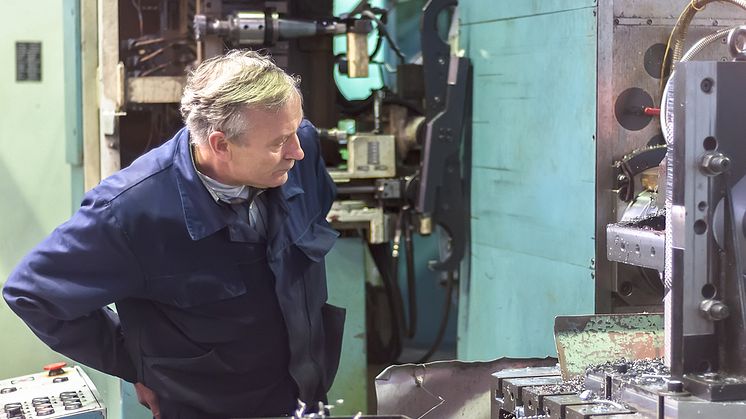 A senior plant production operator inspects a milling machine. Could partial-retirement help him to remain in the workforce for longer? Image: Sergei Butorin / Shutterstock.com