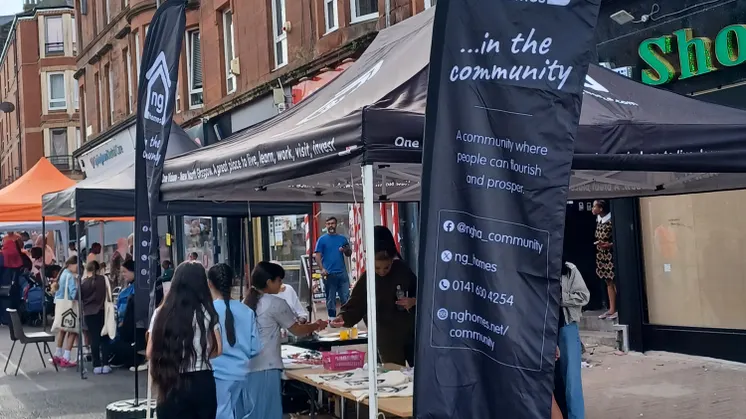 ng homes branded flags and gazebo with residents in front of festival stalls