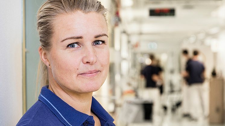 Mari Andersson har sett hur viktig konsten kan vara för patienterna och deras anhöriga. Foto: Anna Molander. Syntolning: Mari i arbetskläder i korridoren på geriatriken.
